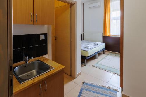 eine Küche mit einem Waschbecken und ein Zimmer mit einem Bett in der Unterkunft Apartments Villa Kobilj in Banja Luka
