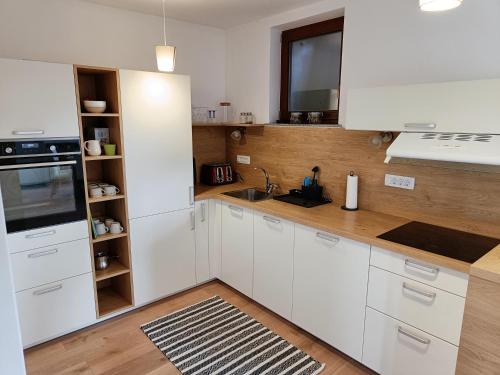 a kitchen with white cabinets and a wooden floor at Green Apartment Cerknica in Cerknica
