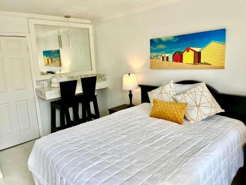a bedroom with a white bed and a kitchen at Colony Club Inn & Suites in Nassau