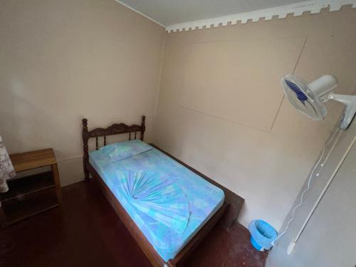 a small room with a bed with a fan at Pura Vida Hostel in Montezuma