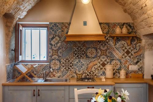 a kitchen with a sink and a window and tiles at Trullo Dell'Erba in Alberobello