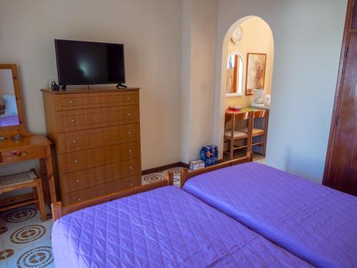 a bedroom with a bed and a dresser with a tv at Eleni's Apartments & Studios 1 in Achílleion