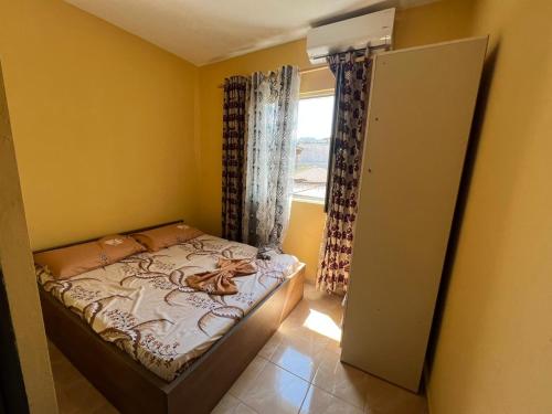 um pequeno quarto com uma cama e uma janela em Veri's house em Tirana