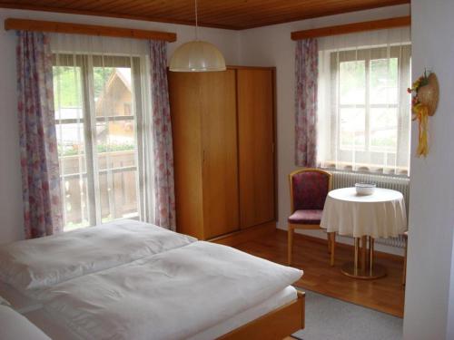 a bedroom with a bed and a table and windows at Haus Meikl in Mühlbach am Hochkönig