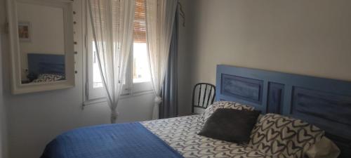 1 dormitorio con 1 cama con cabecero azul y ventana en BLAU, en Masnou