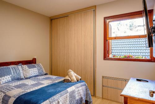 a bedroom with a bed and a window at Charmoso Apartamento no Centrinho de Capivari in Campos do Jordão
