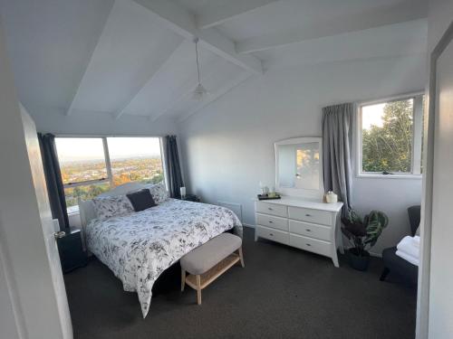 a bedroom with a bed and a dresser and windows at Home with a view in Otorohanga