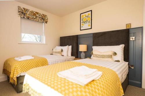 a bedroom with two beds with yellow and white sheets at The Halt @ The Halfway House Country Pub in The Sheddings