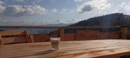 a glass of milk sitting on a wooden table on a deck at Enklawa w Porębie in Długopole-Zdrój