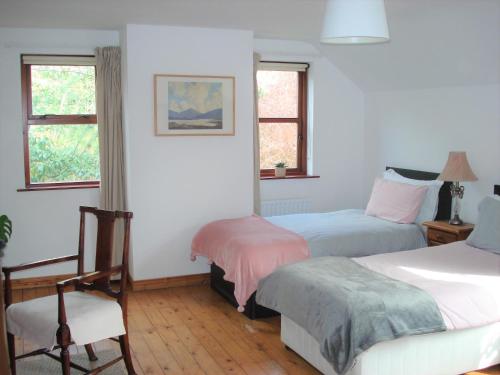 1 dormitorio con 2 camas, 1 silla y 2 ventanas en Ballycastle Glenview House 4 bedrooms in the Glens of Antrim en Ballycastle