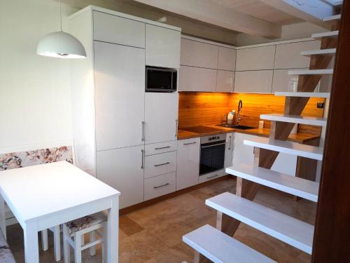 姆龍戈沃的住宿－Nad stawem，厨房配有白色橱柜、白色桌子和楼梯。