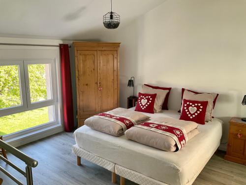 sypialnia z łóżkiem z białymi i czerwonymi poduszkami w obiekcie Gite Au sauna de l’Aubach w mieście Scherwiller