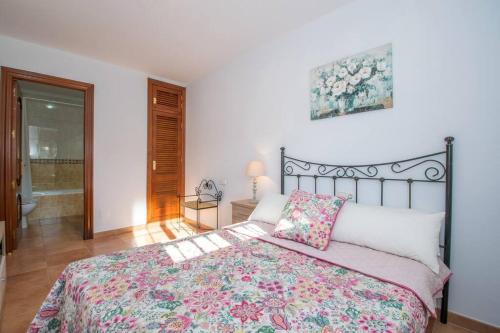 a bedroom with a large bed with a floral bedspread at Bonito apartamento en Frigiliana in Frigiliana