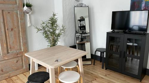 a living room with a wooden table and a tv at Viesu nams Stella in Ventspils