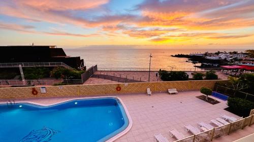 プエルト・デ・サンティアゴにあるSerigor Bahía Ocean Viewの- 海の夕日を望むスイミングプール