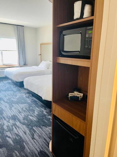 a hotel room with two beds and a tv on a shelf at Fairfield Inn & Suites by Marriott Staunton in Staunton