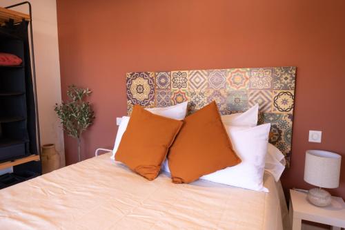 - une chambre avec un lit aux murs orange et des oreillers dans l'établissement Lumineux, tout confort, Wifi & Terrace & Parking, à Saint-Laurent-du-Var