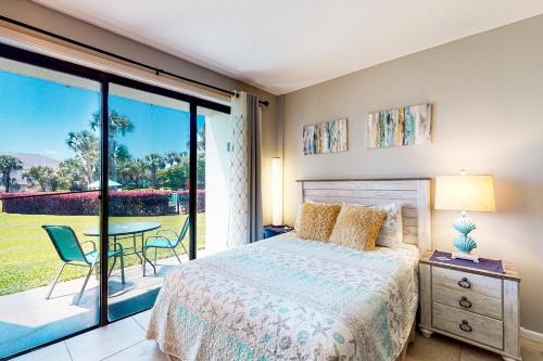 a bedroom with a bed and a balcony with a table at Pirates Bay A104 in Fort Walton Beach