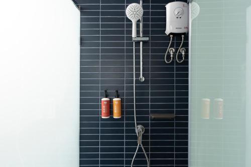 a blue tiled shower with tools on the wall at GO Hotel Ban Chang at Robinson Lifestyle Ban Chang in Ban Chang