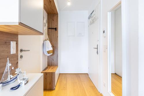 a kitchen with white cabinets and a wooden floor at The Splash by JR City Apartments in Vienna