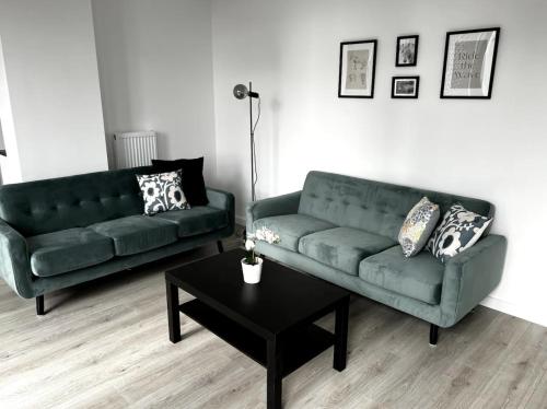 a living room with two green couches and a table at Manhattan Pad in London