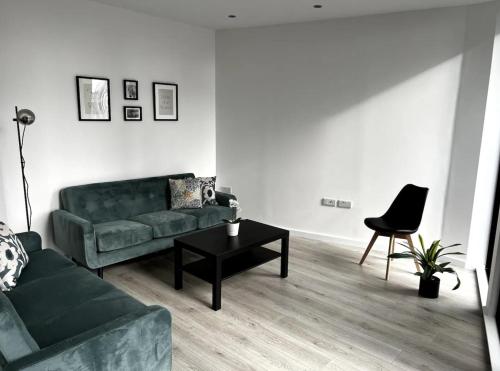 a living room with a green couch and a table at Manhattan Pad in London