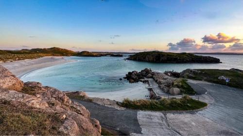 a beach with blue water and rocks in the ocean at Stunning riverside cottage in central location in Donegal