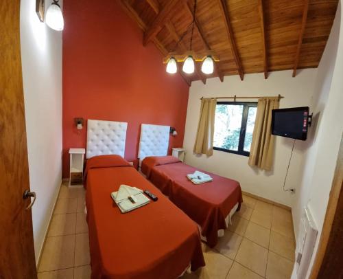 due letti in una stanza con pareti rosse di Cabaña La Victoria a Santa Teresita