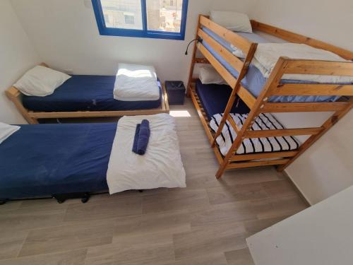 a room with two bunk beds and a wooden floor at Yvonne's Hikers Base Sde Boker in Midreshet Ben Gurion