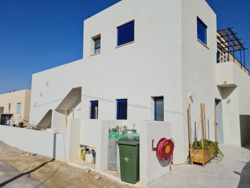 a white building with a green trash can in front of it at Yvonne's Hikers Base Sde Boker in Midreshet Ben Gurion