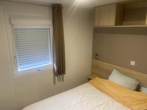 een kleine slaapkamer met een bed en een raam bij Vacance à la Carabasse in Vias