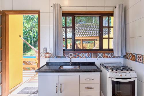 a kitchen with a sink and a stove at Studios na Vermelhinha in Ubatuba
