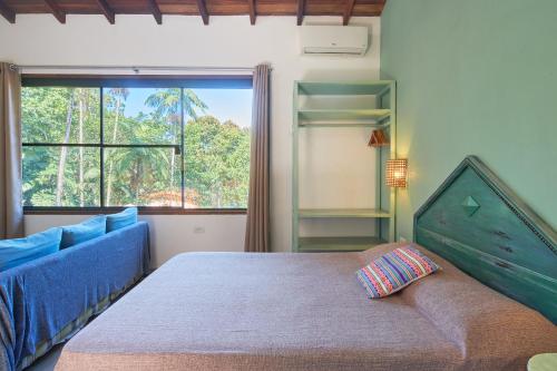 a bedroom with a bed and a couch and a window at Studios na Vermelhinha in Ubatuba