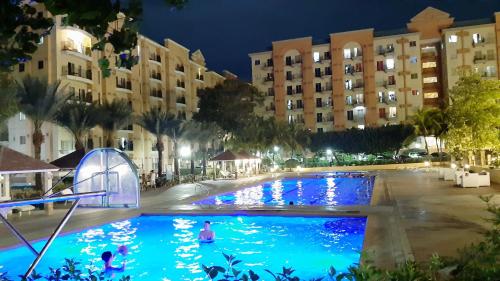 una piscina por la noche con gente nadando en ella en Legaspi Loft Suite, en Manila