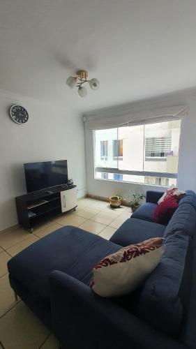 a living room with a blue couch and a television at DEPARTAMENTO BREÑA POR Hospital LOAYZA in Lima