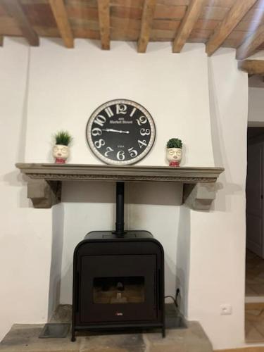 a clock sitting on a shelf above a fireplace at Teo’s house è la casa ideale per il relax in Anghiari