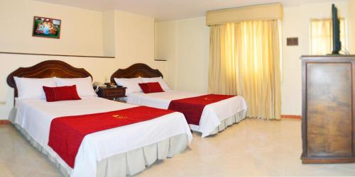 a bedroom with two beds with red and white sheets at Hotel Plaza Versalles in Cali