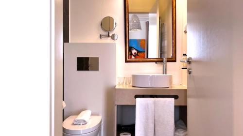 ein Badezimmer mit einem Waschbecken, einem WC und einem Spiegel in der Unterkunft Jardim da Lapa by Shiadu in Lissabon