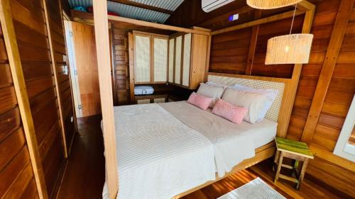 a bedroom with a bed with two pink pillows at Ilha do Mel Lodges in Ilha do Mel