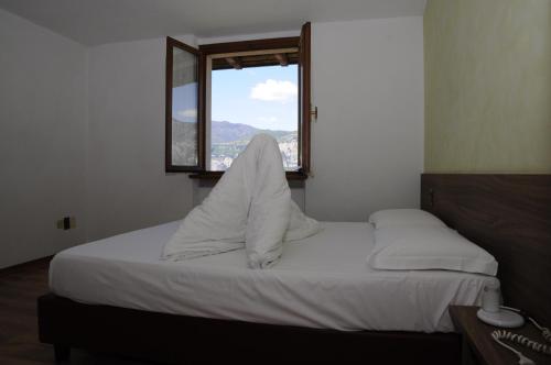 a bedroom with a bed with white sheets and a window at Casa Guarnati Lake View Apartments in Malcesine