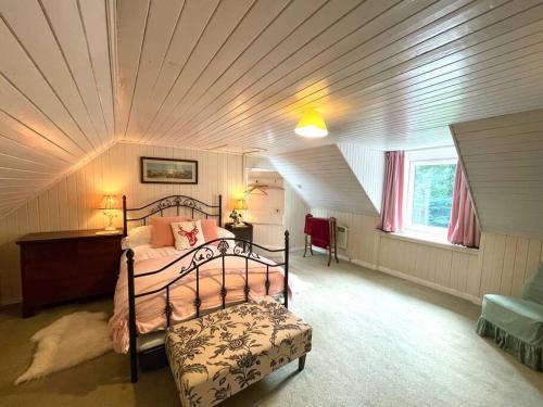 ein Schlafzimmer mit einem Bett im Dachgeschoss in der Unterkunft Traditional farm cottage with woodburner by stream in Cladich