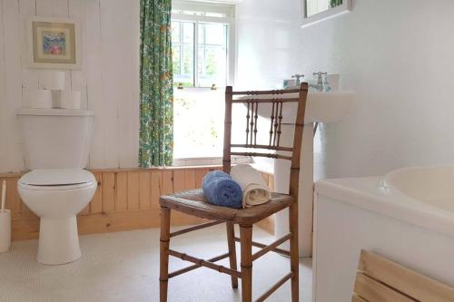 ein Badezimmer mit einem WC und einem Stuhl mit einem Waschbecken in der Unterkunft Traditional farm cottage with woodburner by stream in Cladich