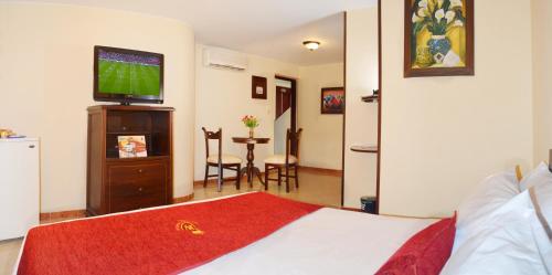 a bedroom with a bed with a television and a table at Hotel Plaza Versalles in Cali