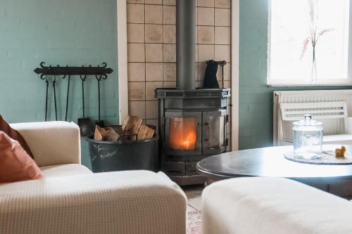 a living room with a wood stove and a table at Boshoes in Heythuysen