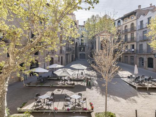 a courtyard with tables and umbrellas in front of a building at Cal Rellotger de Solsona in Solsona