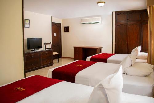 a hotel room with two beds and a television at Hotel Plaza Versalles in Cali