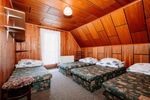 two beds in a room with wood paneled walls at Chata Kokava Línia in Kokava na Rimavica