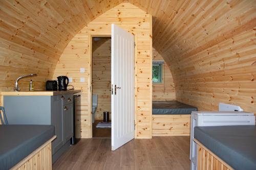 a small kitchen with a door in a wooden cabin at Glamping Pod 2 Magical Craigengillan Estate in Dalmellington