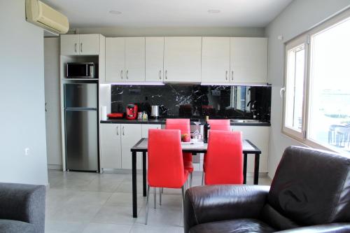 a kitchen with a dining table and red chairs at MAXIM APARTMENT in Heraklio