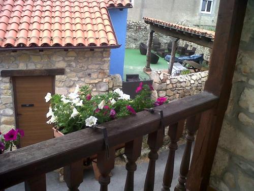 einen Balkon mit Blumen und ein Haus mit einem Gebäude in der Unterkunft El Cabañon de Pimiango in Pimiango